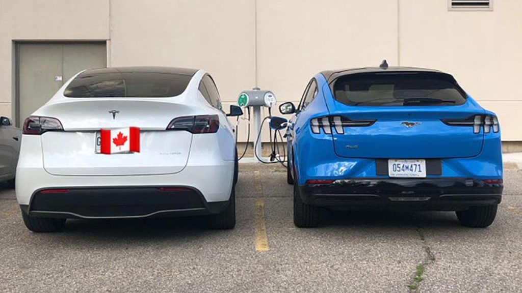 Tesla Model Y side-by-side with the Ford Mach-E prototype, both cars charging.