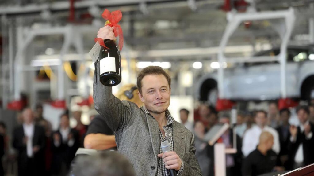 Elon Musk holding champagne in hand as celebration.
