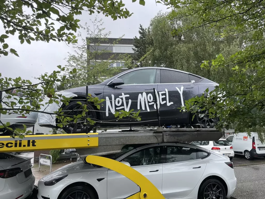Tesla Model Y electric SUVs getting delivered to a Tesla Store in Europe (one showroom Model Y with "Not Model Y" sticker on the side profile).