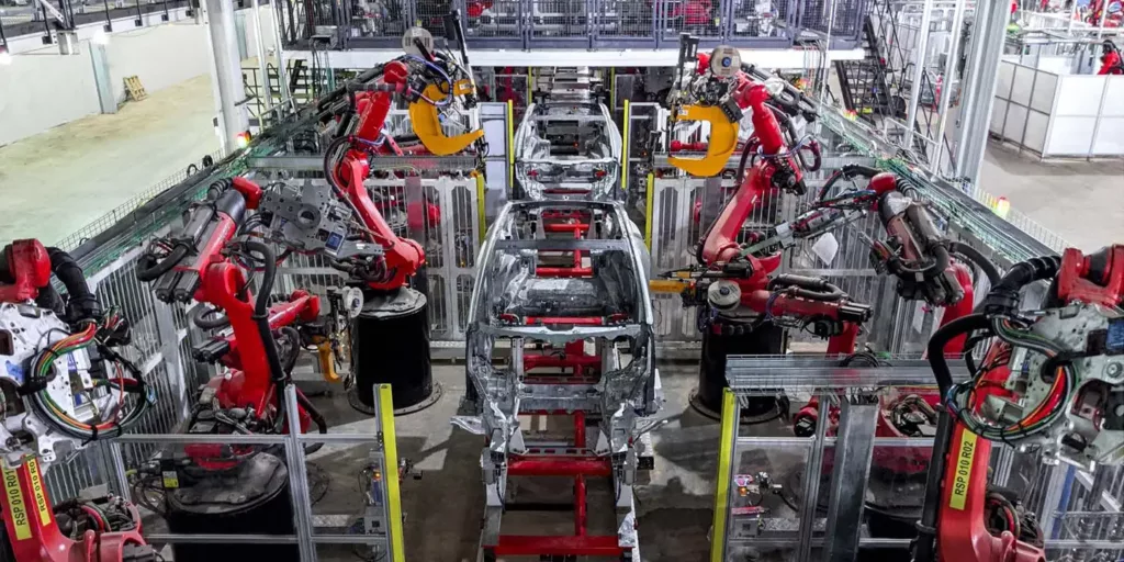 Tesla Model Y body shop at Giga Texas as of Q2 2021. Model Y body frames can be seen on an assembly line with robots at work.