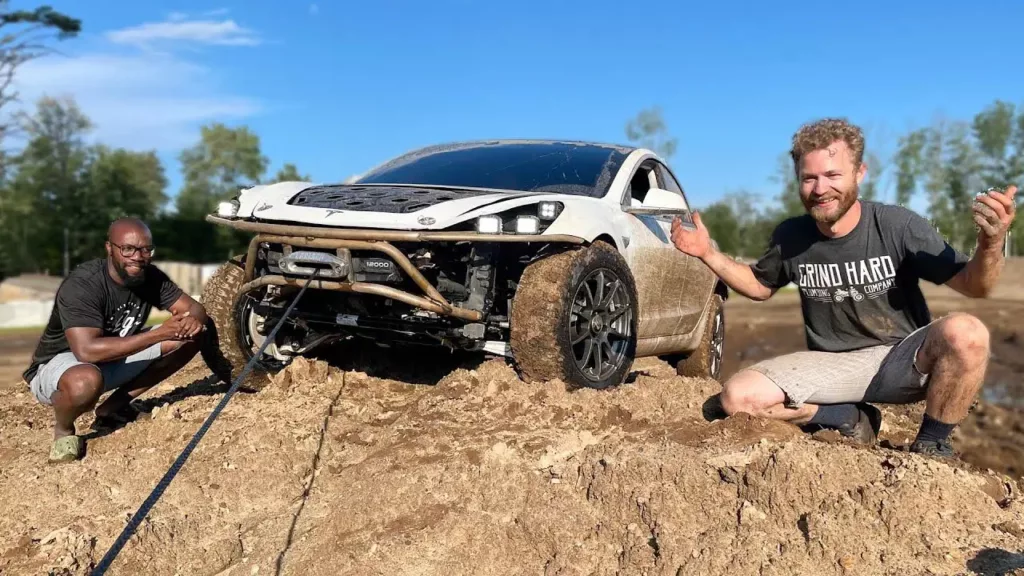 YouTubers Rich Rebuilds (L) and Grind Hard Plumbing Co (R) show off their modified Tesla Model 3 EV off-roader.