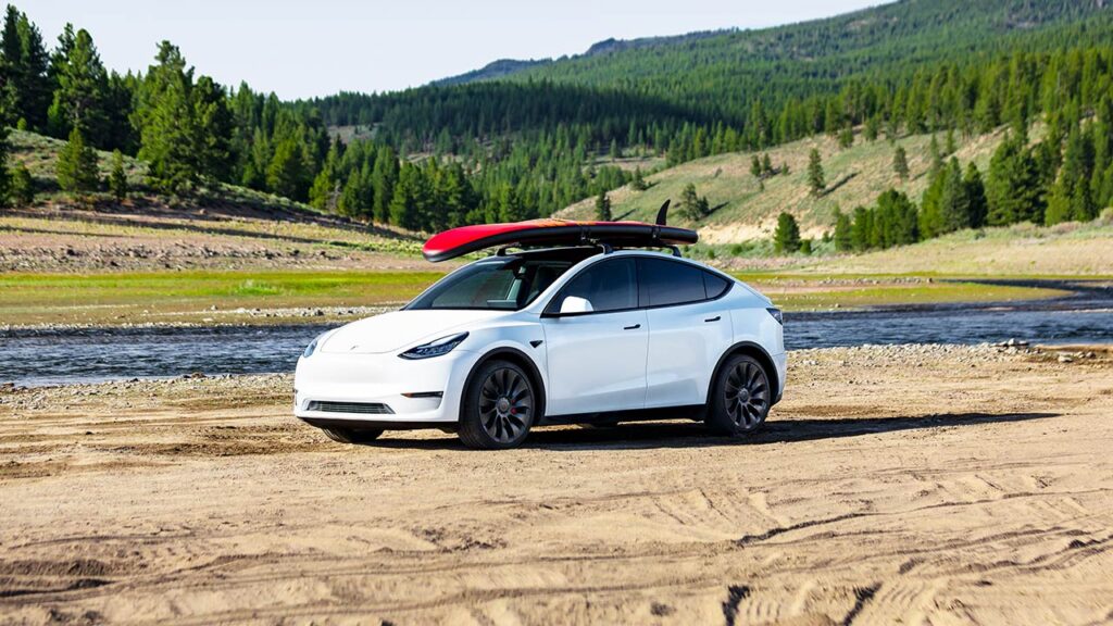 Tesla Model Y with a surfboard on its roof.