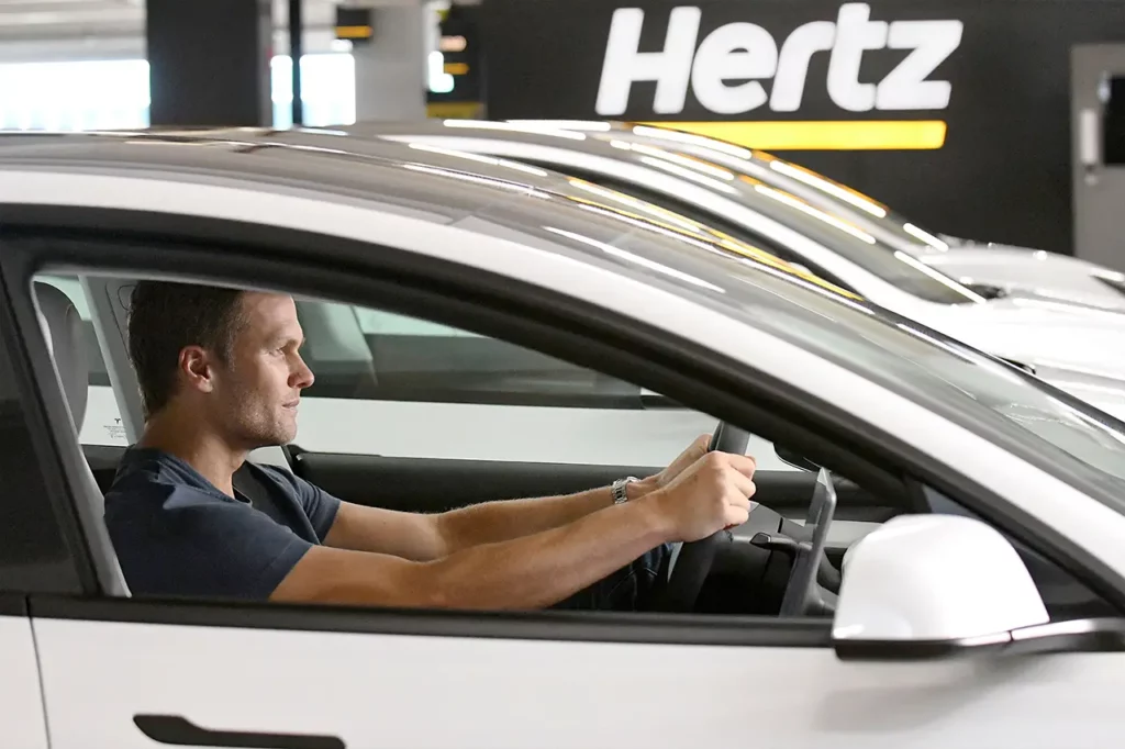 Tom Brady driving a Tesla Model 3 rental car by Hertz.