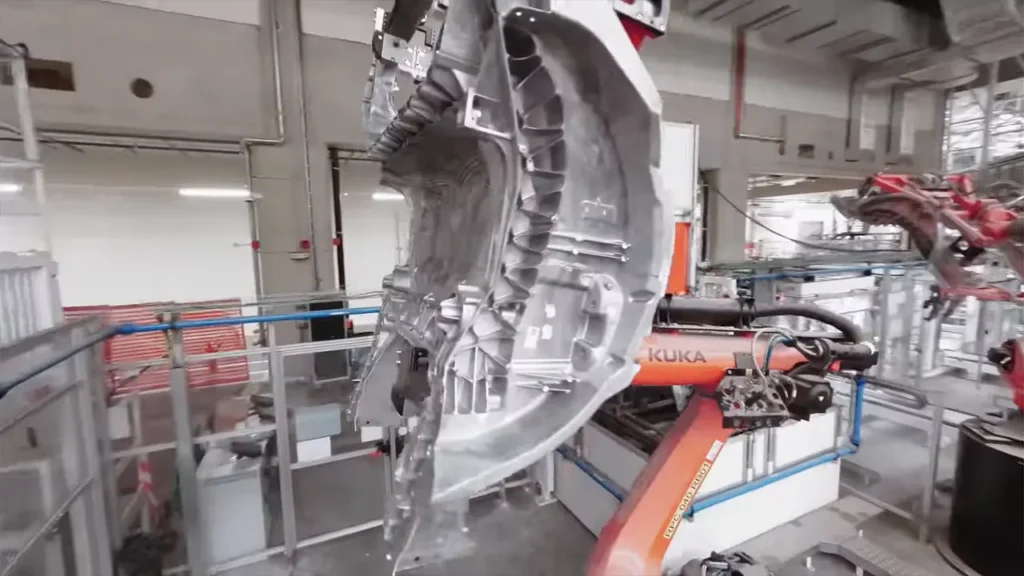 A Kuka robot holding a Tesla Model Y single-piece underbody casting after receiving it from the Giga Casting machine at Gigafactory Berlin.
