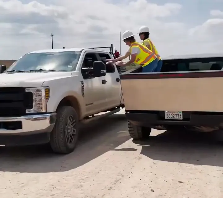 Giga Texas employees serving ice cream to other workers seated in a Ford F-250 Super Duty pickup truck from the bed of the Cybertruck.
