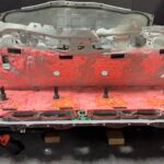 Tesla Model Y structural battery pack in the process of its teardown. The hard metal cover on top is not easy to remove.