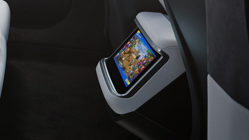 Press photo of a design update of the Tesla Model S (2021-later) interior showing a video game playing on the smaller rear screen.