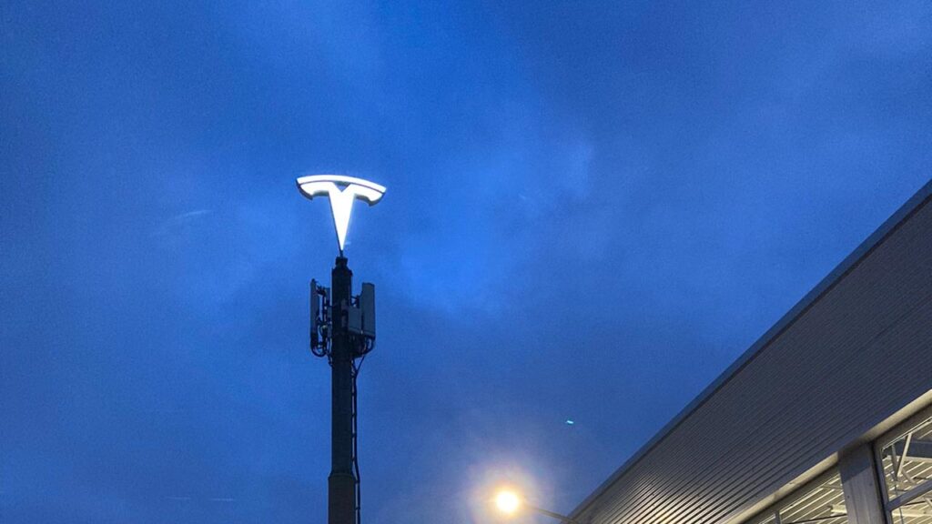 Tesla logo installed on a high tower at a Tesla Store and Service Center in the Netherlands.