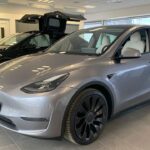 Tesla Model Y electric SUV in Quicksilver color parked inside a Tesla Showroom & Store in Germany.