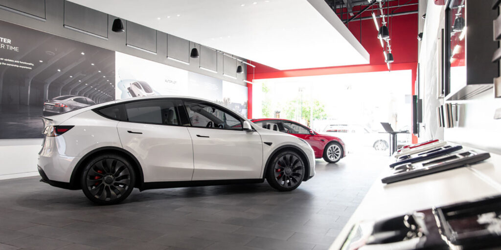 A Tesla sales showroom from the inside (white Tesla Model Y in front, red Model 3 in the background).