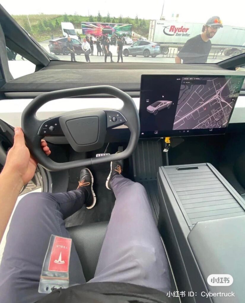 Tesla Cybertruck interior from the driver's POV (cyber steering, dashboard, center console, and the center touchscreen are clearly visible).