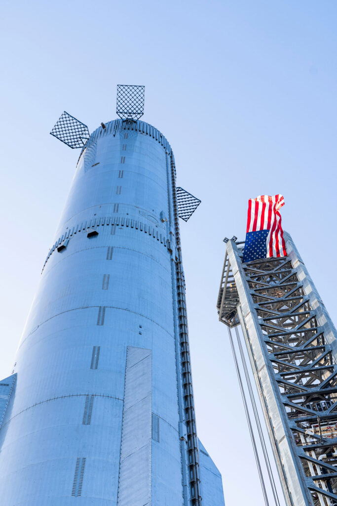American flag raised at the Starship launch integration tower as Booster 9 reaches the OLM at Starbase, Texas on Friday 21st July 2023.