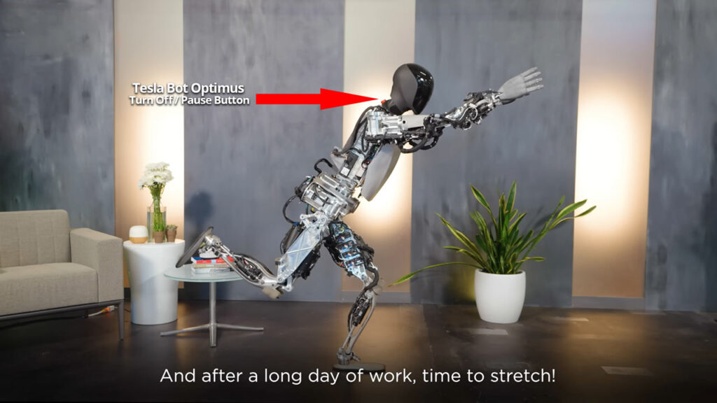 Tesla's humanoid robot Optimus demonstrates a stretching posture that exposes its turn on;/off/pause button behind the robot's neck.