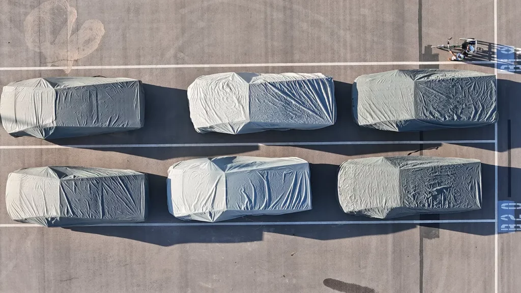 Six covered Tesla Cybertruck electric pickup trucks parked outside Giga Texas. Spotted in aerial footage on 2nd October 2023.