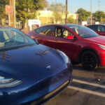 Multiple Tesla Model Y electric SUVs charging at a Tesla Supercharger station.