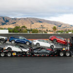 A Tesla Semi truck with a car carrier trailer loaded with Model Y, Model 3, Model S, and a Cybertruck.