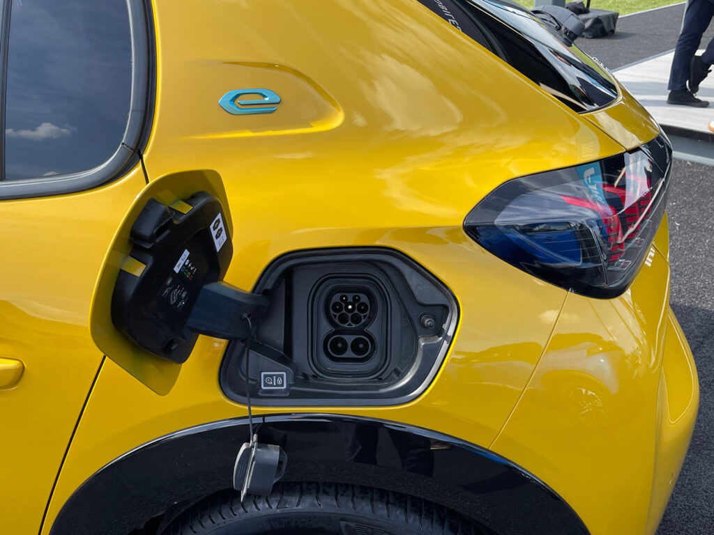 Open charge port of a Peugeot e-208 EV in yellow color ready to be charged for its next journey.