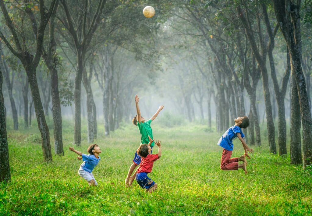 Healthy children playing football in a green and clean air environment.