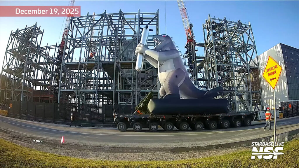 A statue of a dinosaur holding a dummy Starship Super Heavy rocket booster during the Starbase Christmas Parade on Friday, 19th December 2025.