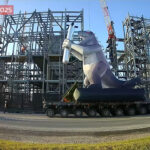 A statue of a dinosaur holding a dummy Starship Super Heavy rocket booster during the Starbase Christmas Parade on Friday, 19th December 2025.