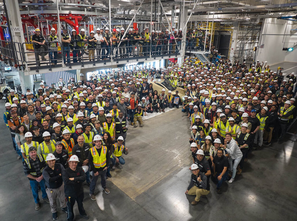 Tesla employees at Giga Texas celebrate as the first Cybercab electric vehicle rolls off the production line.