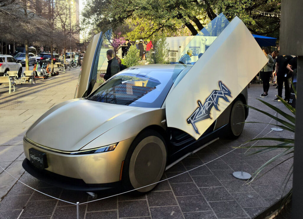 A Tesla Cybercab on display in Austin, Texas. The Robotaxi logo is visible on the butterfly door.