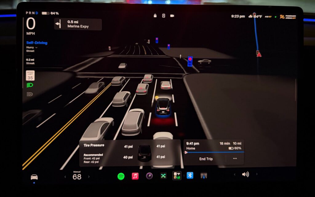 Tesla FSD v14.3.3 driving visualizations in heavy traffic as the vehicles approach a red light.