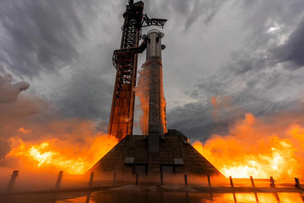 The flame trench deflects the heat and flames as Booster 20 goes through a 33-engine static fire test at Starbase, Texas, on July 10, 2026.