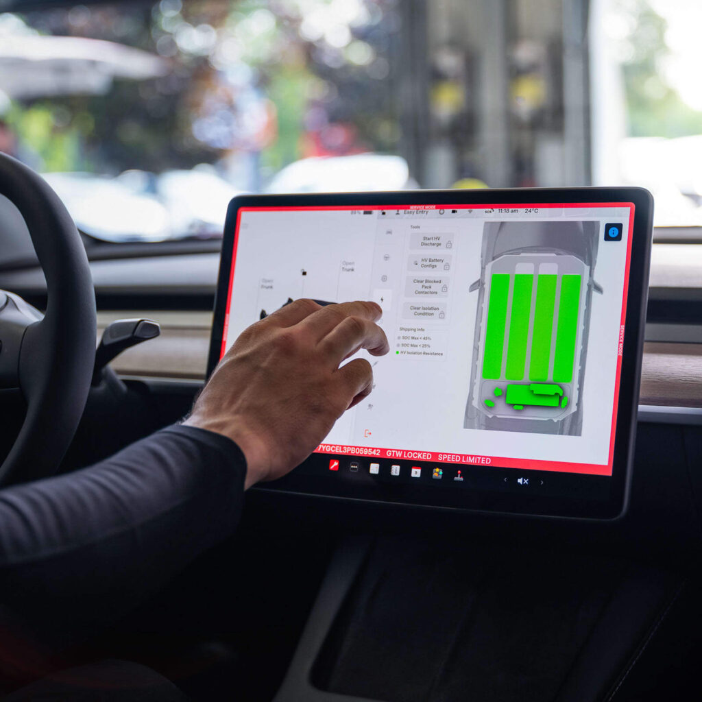 A Tesla technician using Service Mode of a Tesla vehicle to check battery health.