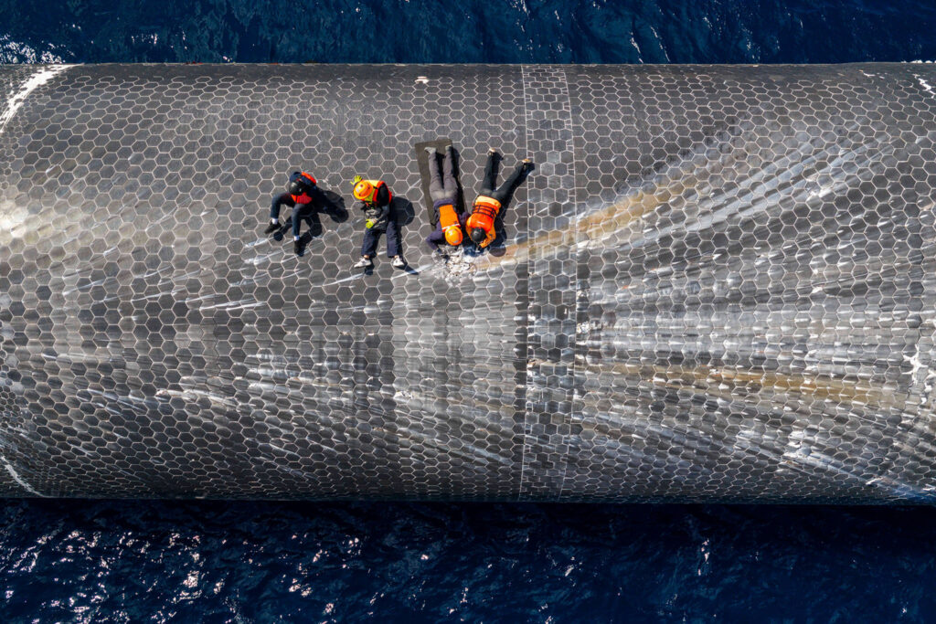 SpaceX engineers inspecting damaged heat shield tiles, while Starship 40 floats on the surface of the Indian Ocean (Christmas Island, Australia).