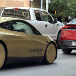A red Tesla Model Y Robotaxi leads a Cybercab on the streets of Austin, Texas.
