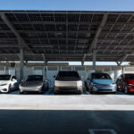 Left to right: Tesla Model S, Model 3 Highland, Cybertruck, Model X, Model Y Juniper charging at a solar-powered Supercharger station (solar panels on roof).